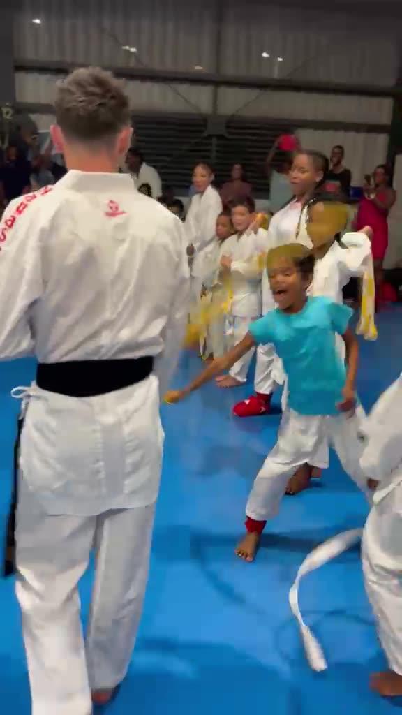 Un encadrant face à des enfants alignés sur le tatami
