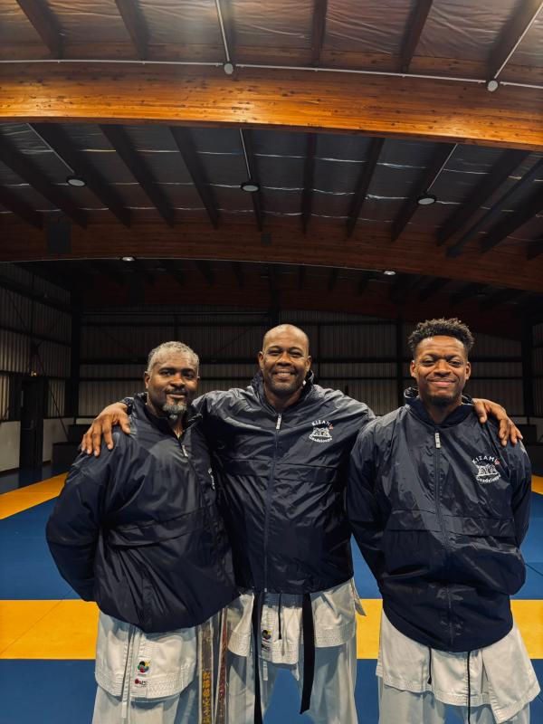 Trois encadrants du club posent sur le tatami du dojo