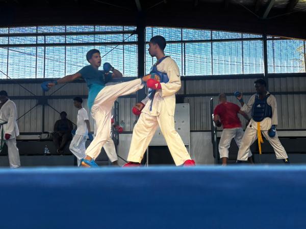 Deux karatékas s’affrontent en kumité sur un tatami bleu